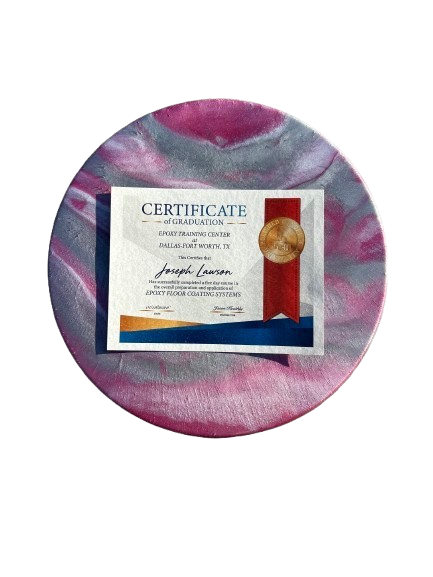 Certificate of graduation with a red ribbon and gold seal, placed on a round, marbled surface.