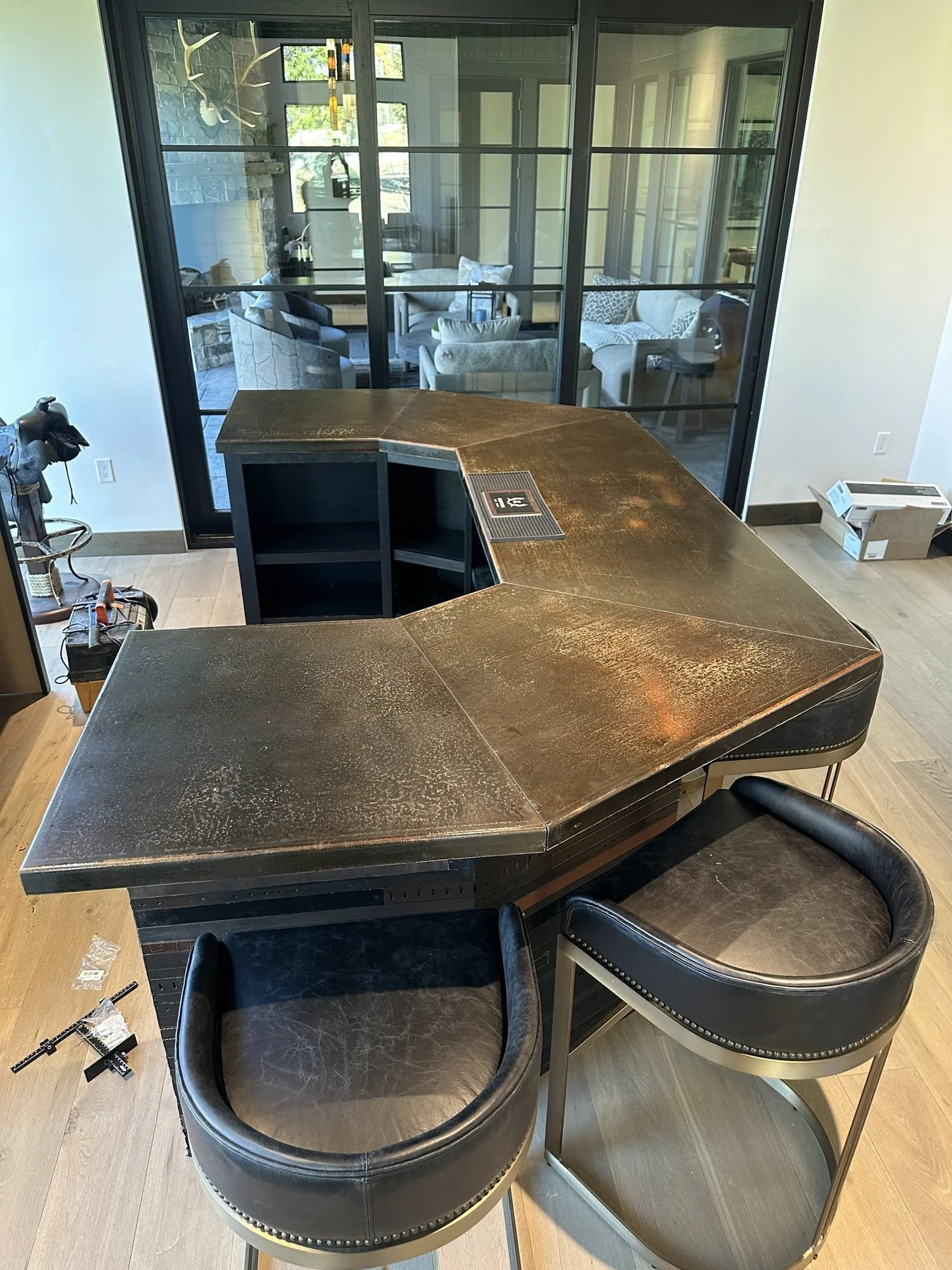 Angled view of the patinaed steel bar island top over its black-stained white oak base