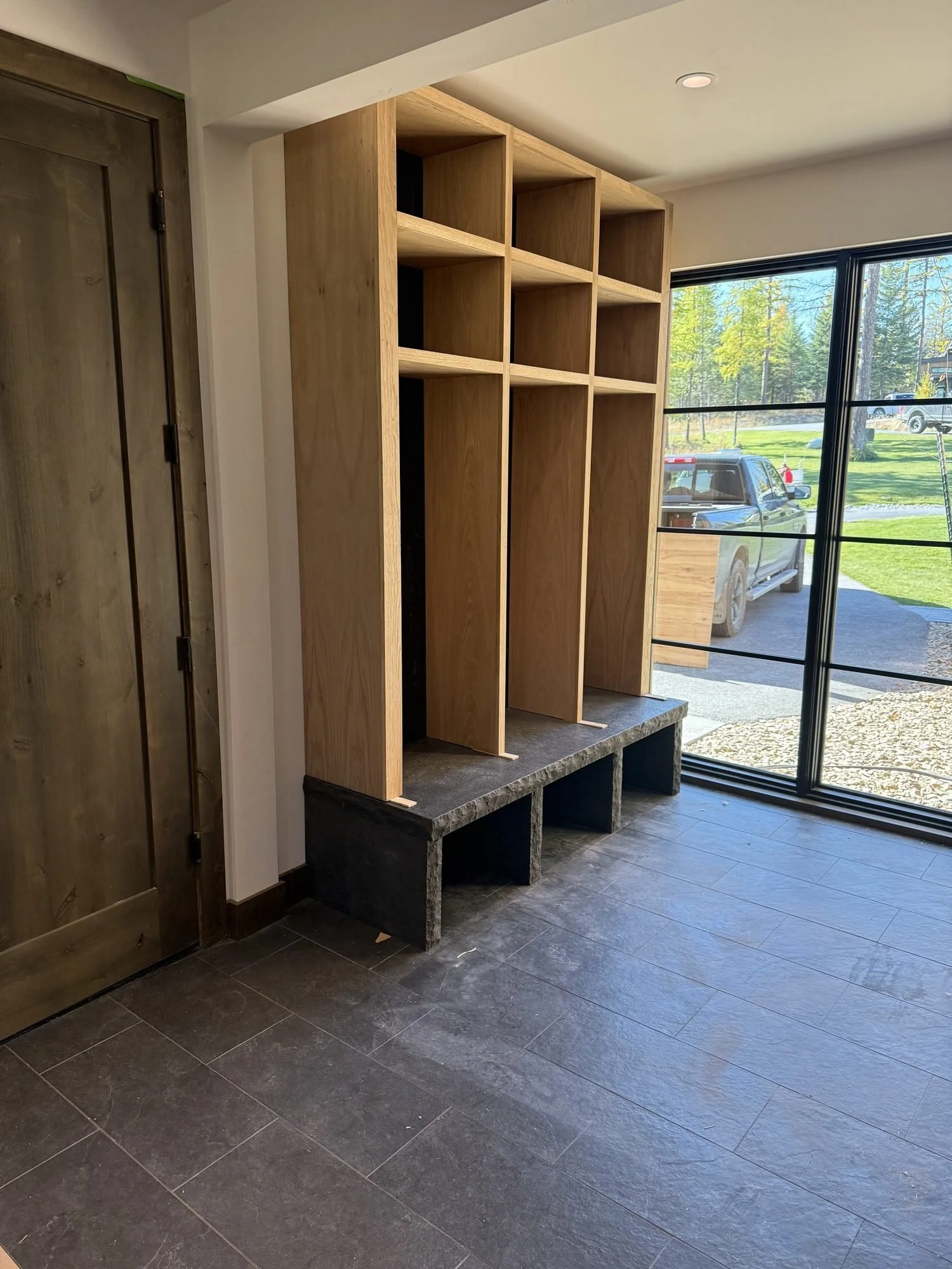 Plain-sawn white oak mudroom lockers with a clear finish and open cubbies above a bench