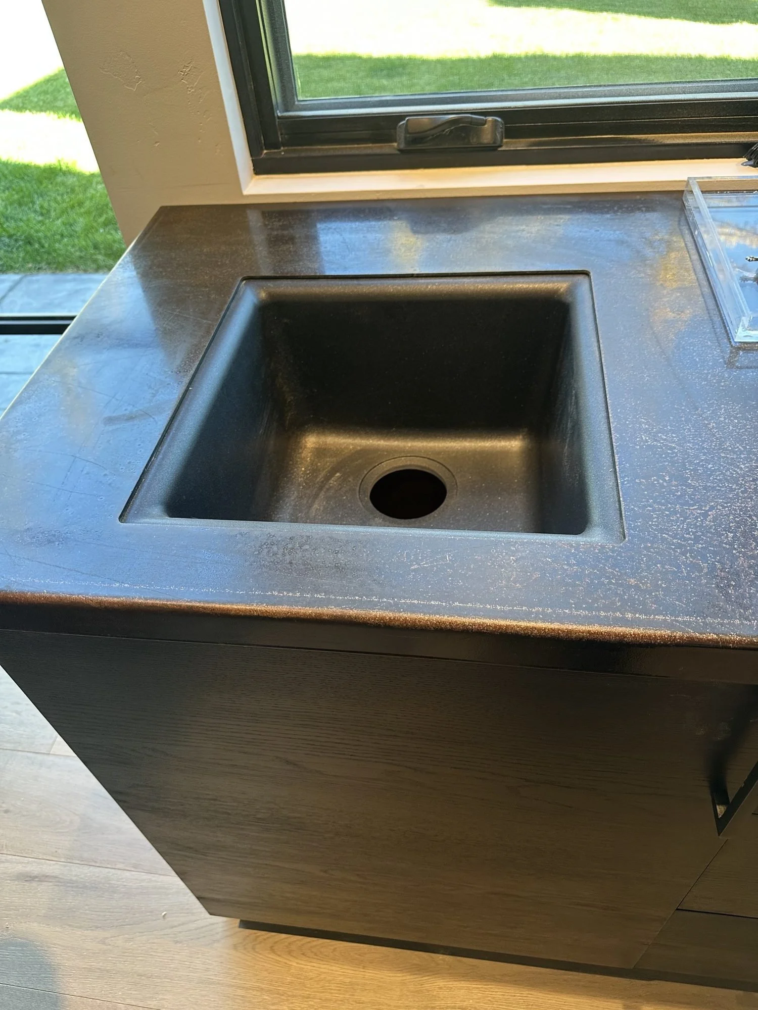 Back bar sink set into a dark top over horizontal rift-sawn white oak cabinetry stained black
