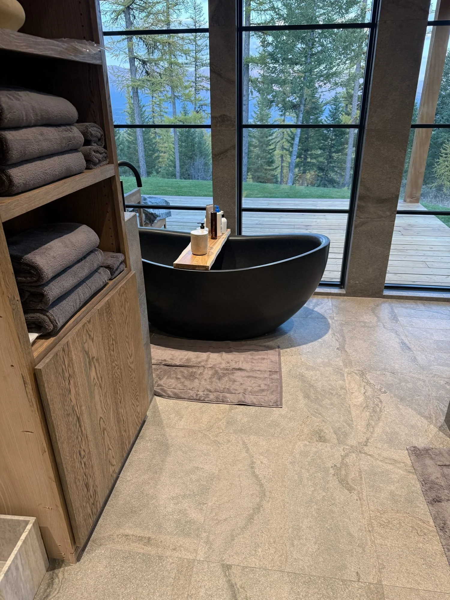 Wire-brushed white oak linen tower beside a freestanding tub and mountain-view windows