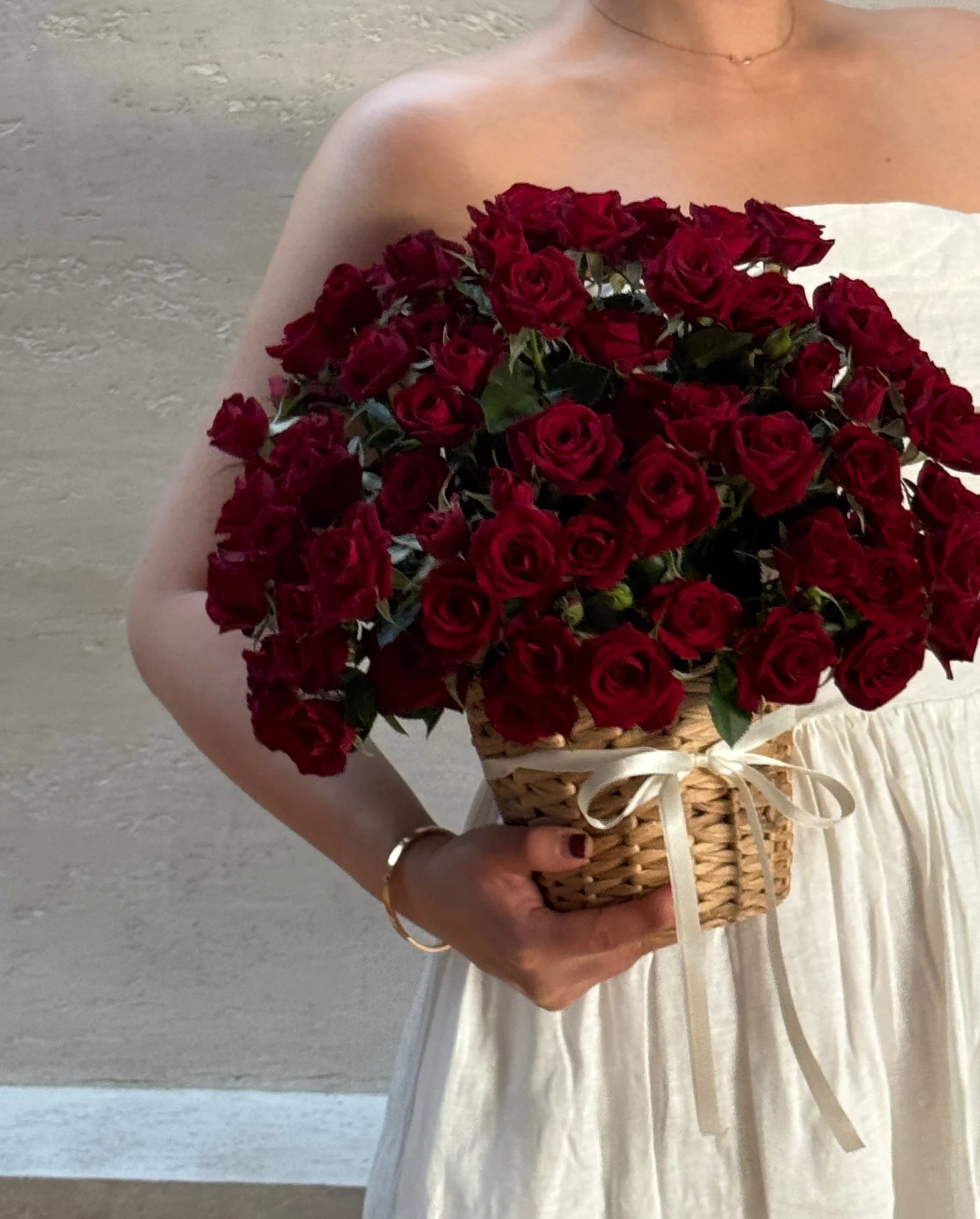 A woman in a white dress holding a basket of red roses