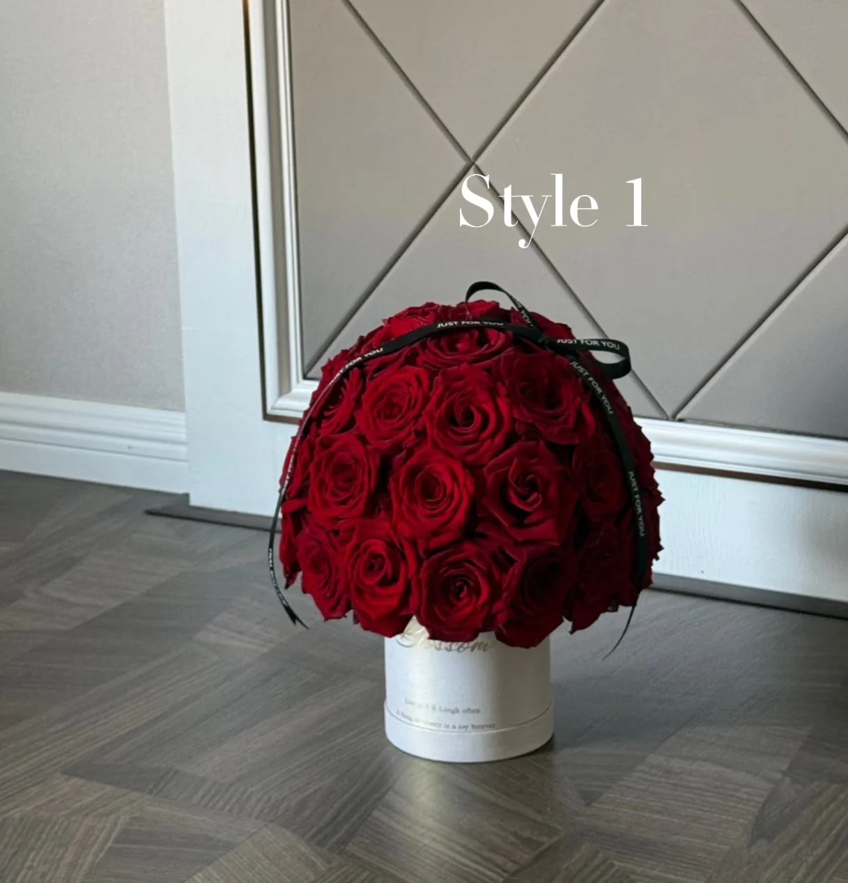 A bouquet of red roses in a white container with a black ribbon that says 'Just For You'. The background features a paneled wall, and the floor is a wooden pattern. Text on the image reads 'Style 1'.