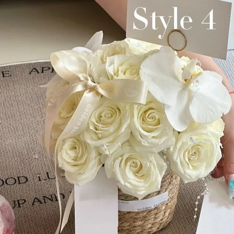 A bouquet of white roses and white orchids wrapped in ribbon and placed in a woven basket, with a sign labeled 'Style 4' attached.