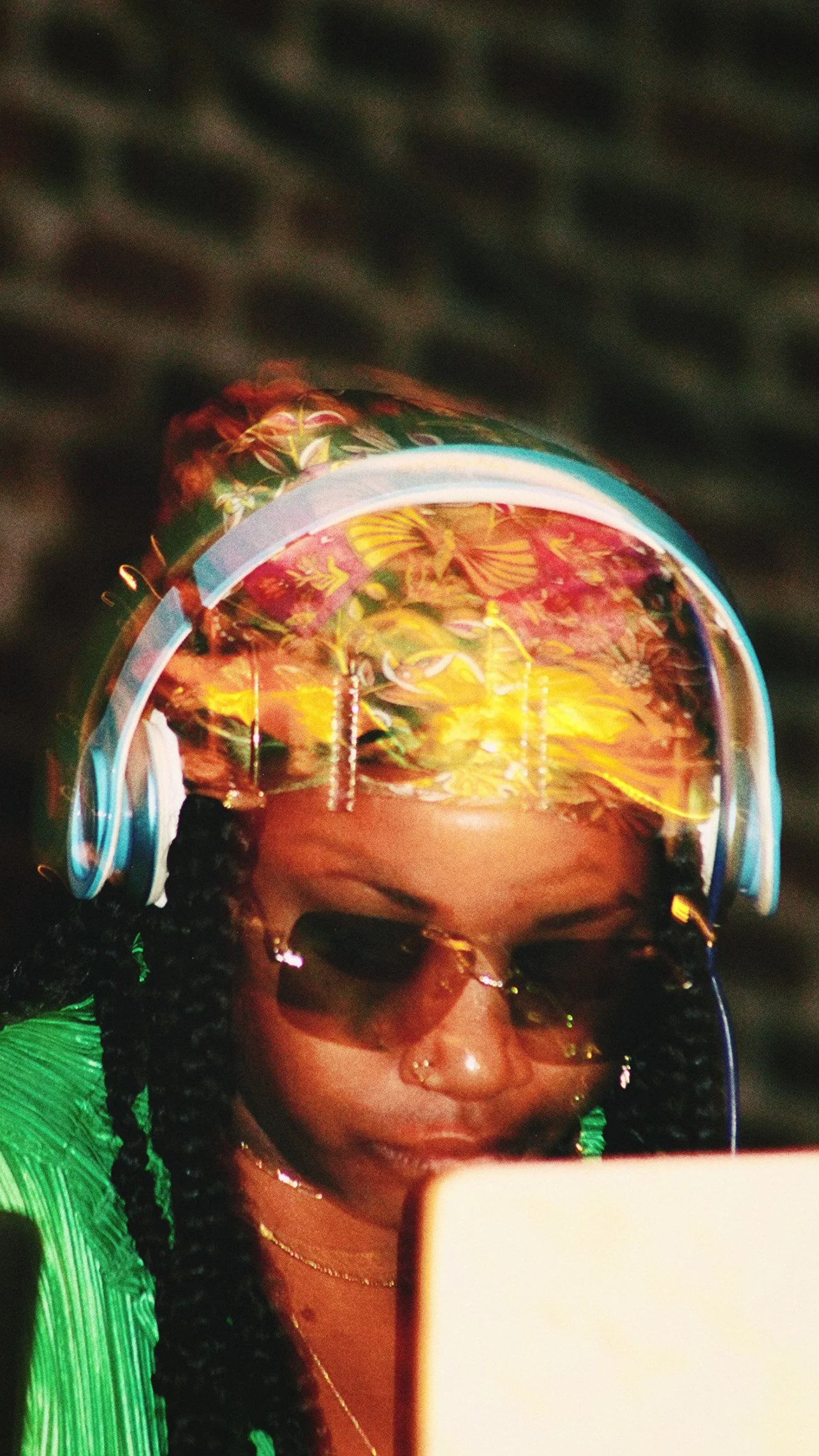 A woman wearing headphones and sunglasses looking at a screen.