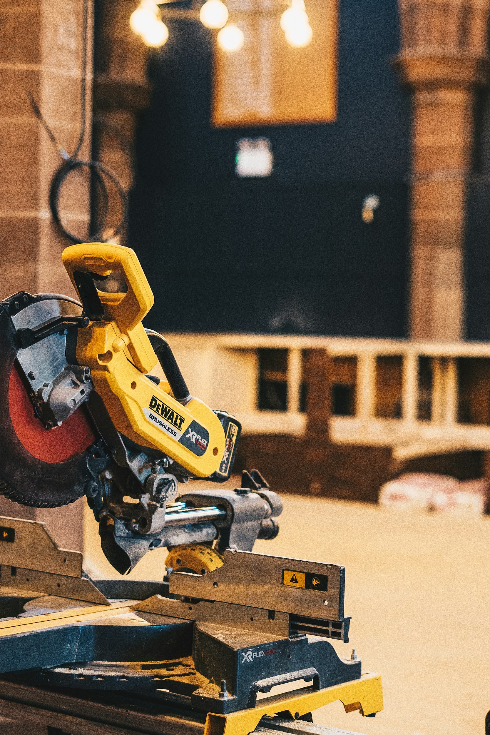 Close-up of a yellow DeWalt cordless circular saw on a wooden workbench in a workshop.