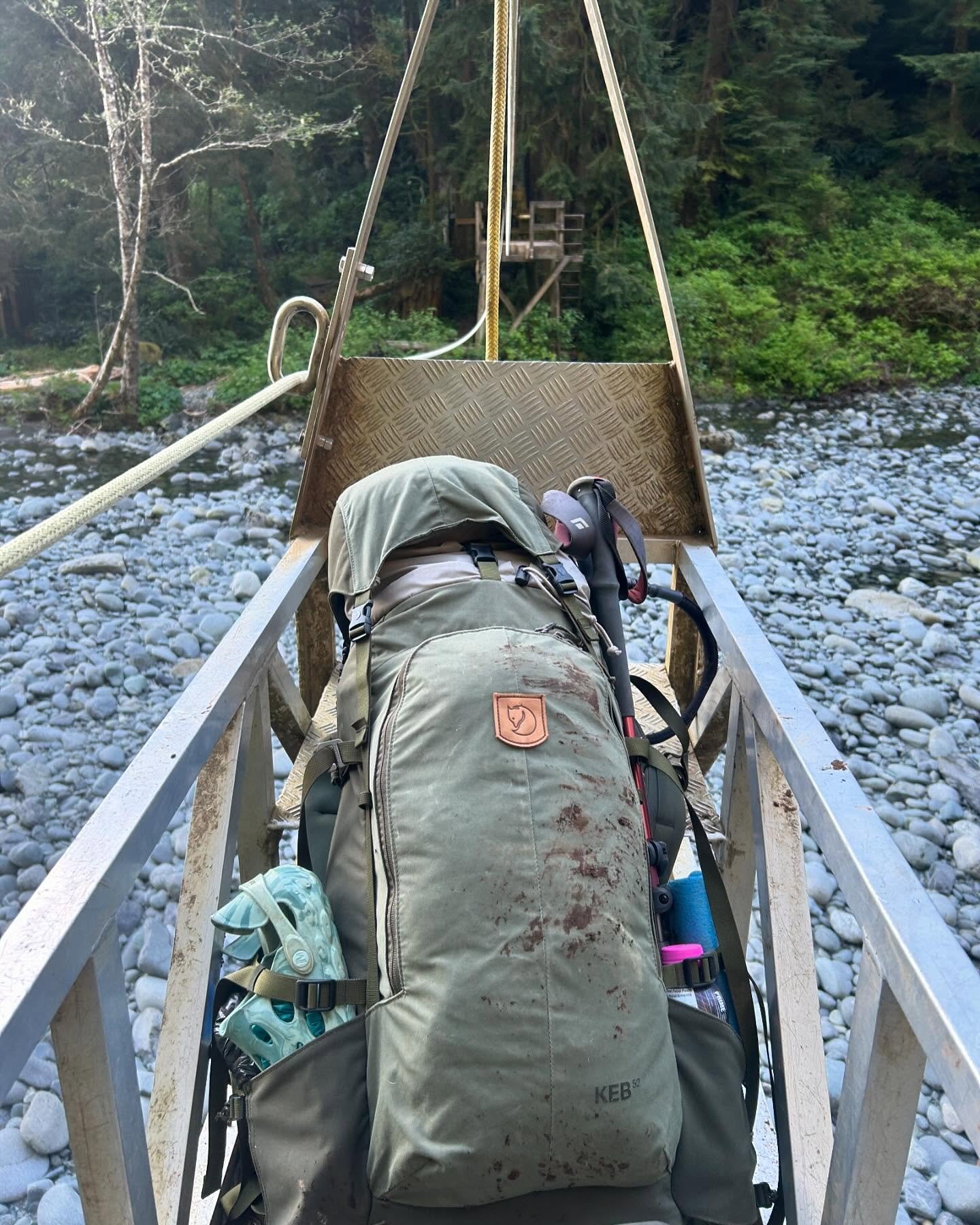 A backpack on a boat on a rocky river with a forested background.
