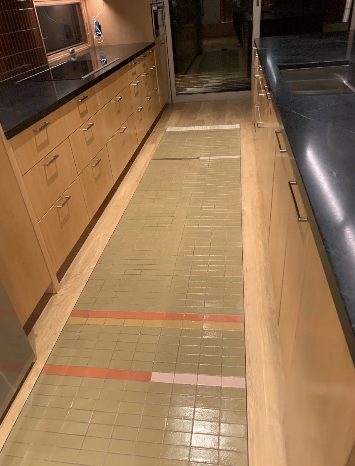 Kitchen with wood cabinets, black countertops, and a green tiled floor.