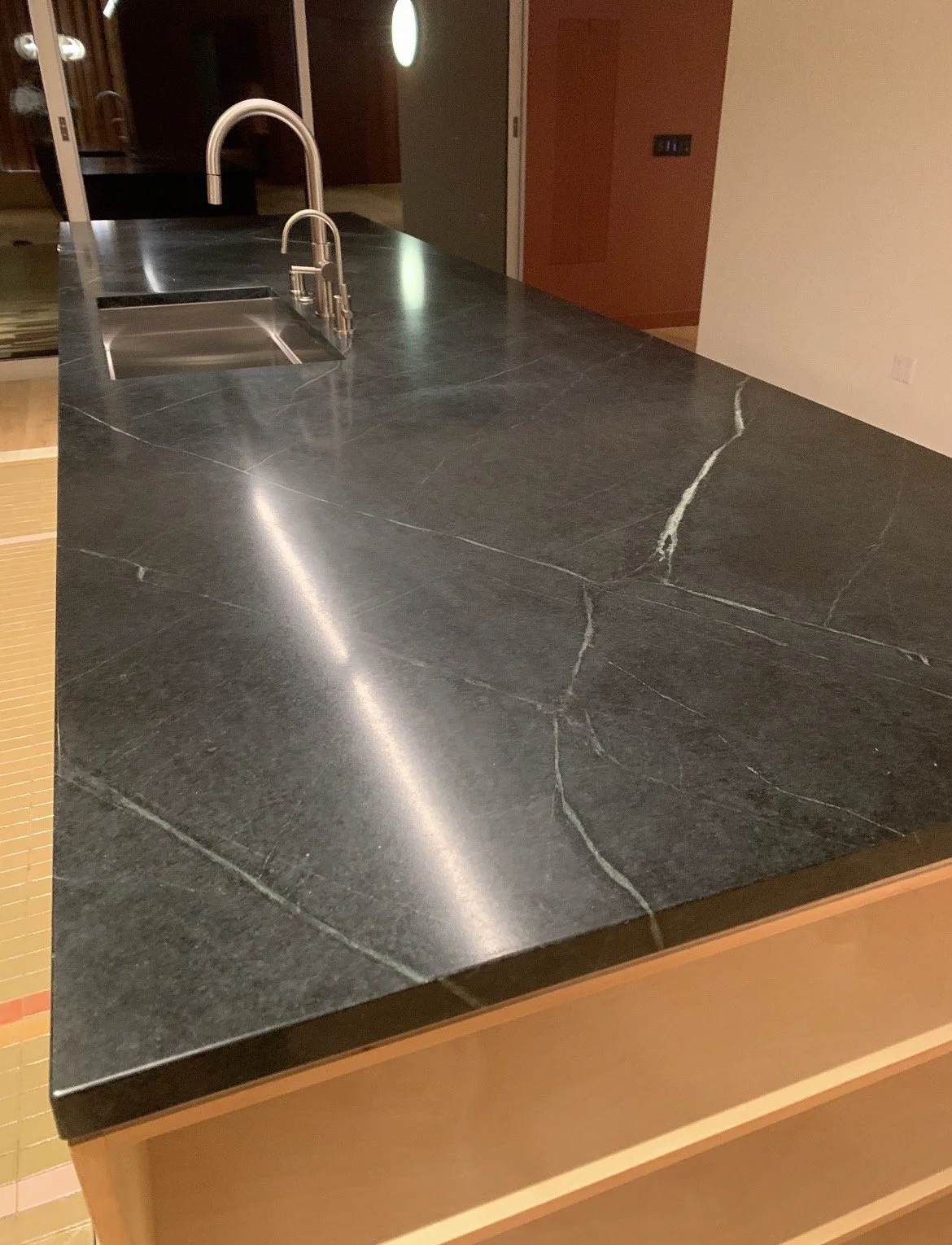 Black marble kitchen countertop with a stainless steel sink and modern faucet.