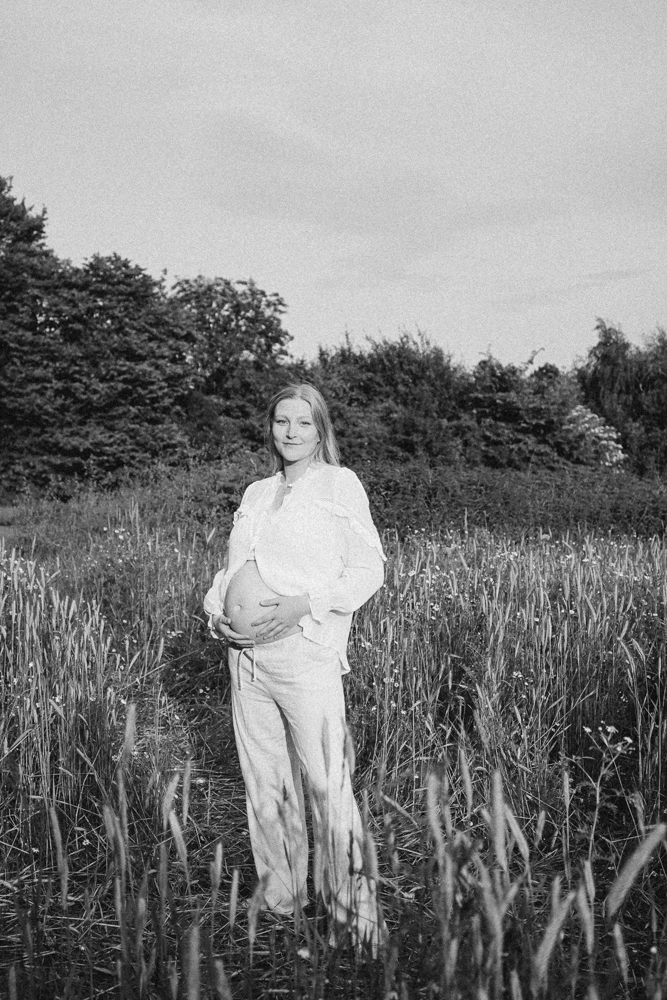 Schwangere Frau in hohen Gräsern im Freien, schwarz-weiß Foto