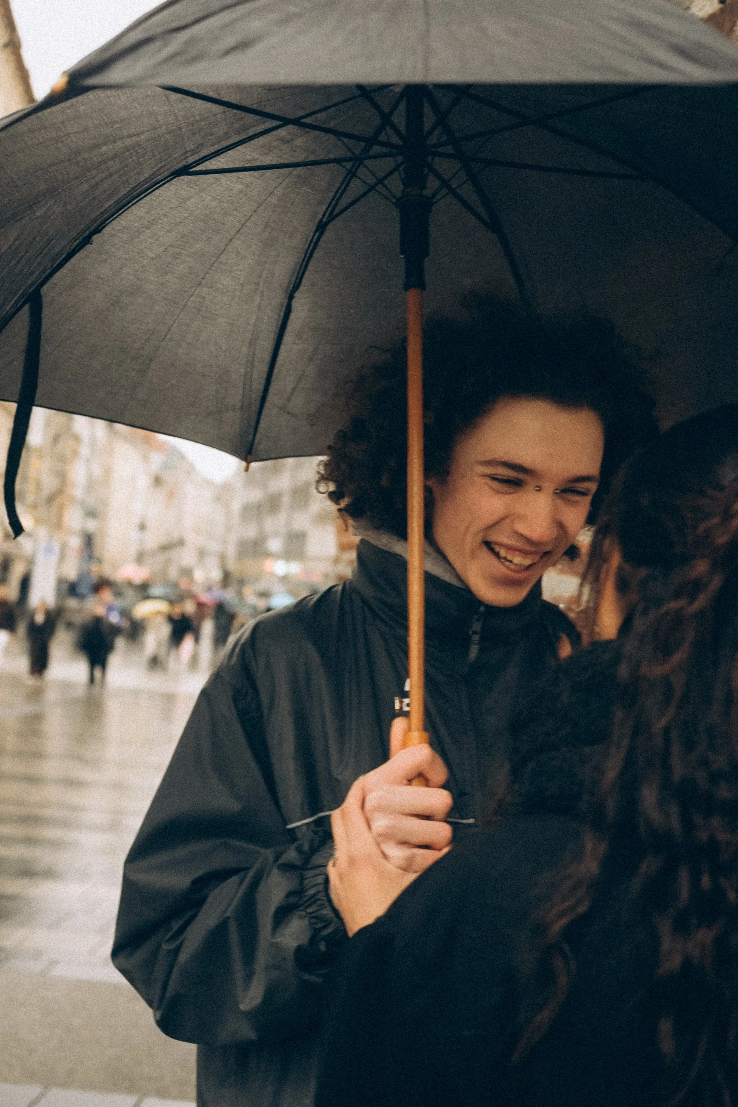Zwei Frauen unter einem Regenschirm auf der Straße bei Regen, lächelnd und in einander verliebt.