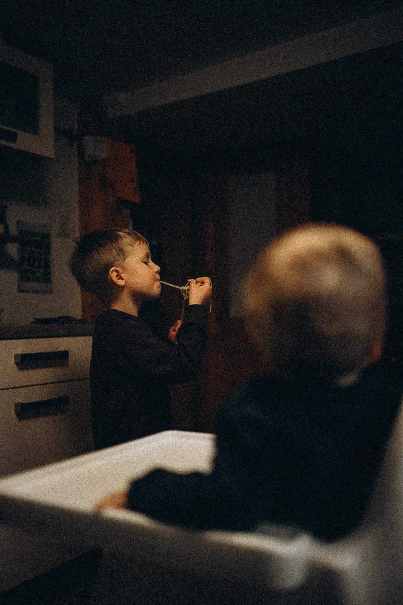 natürliche Familienfotografie in Kassel Kind isst Nudeln in der Küche zuhause