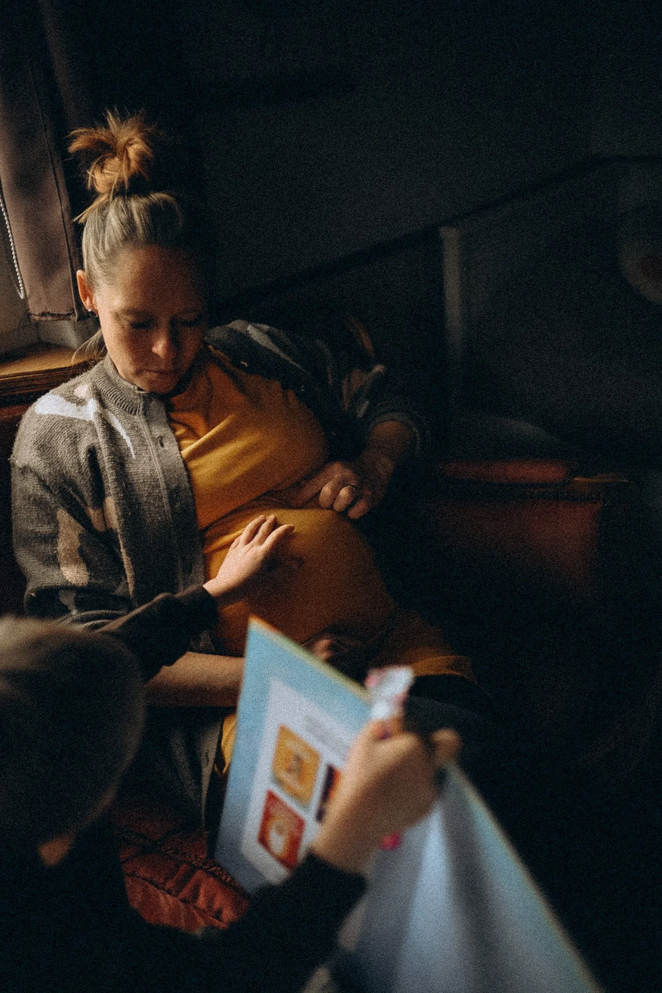 natürliche Familienfotografie in Kassel Kind berührt Schwangeren Bauch während dem Vorlesen