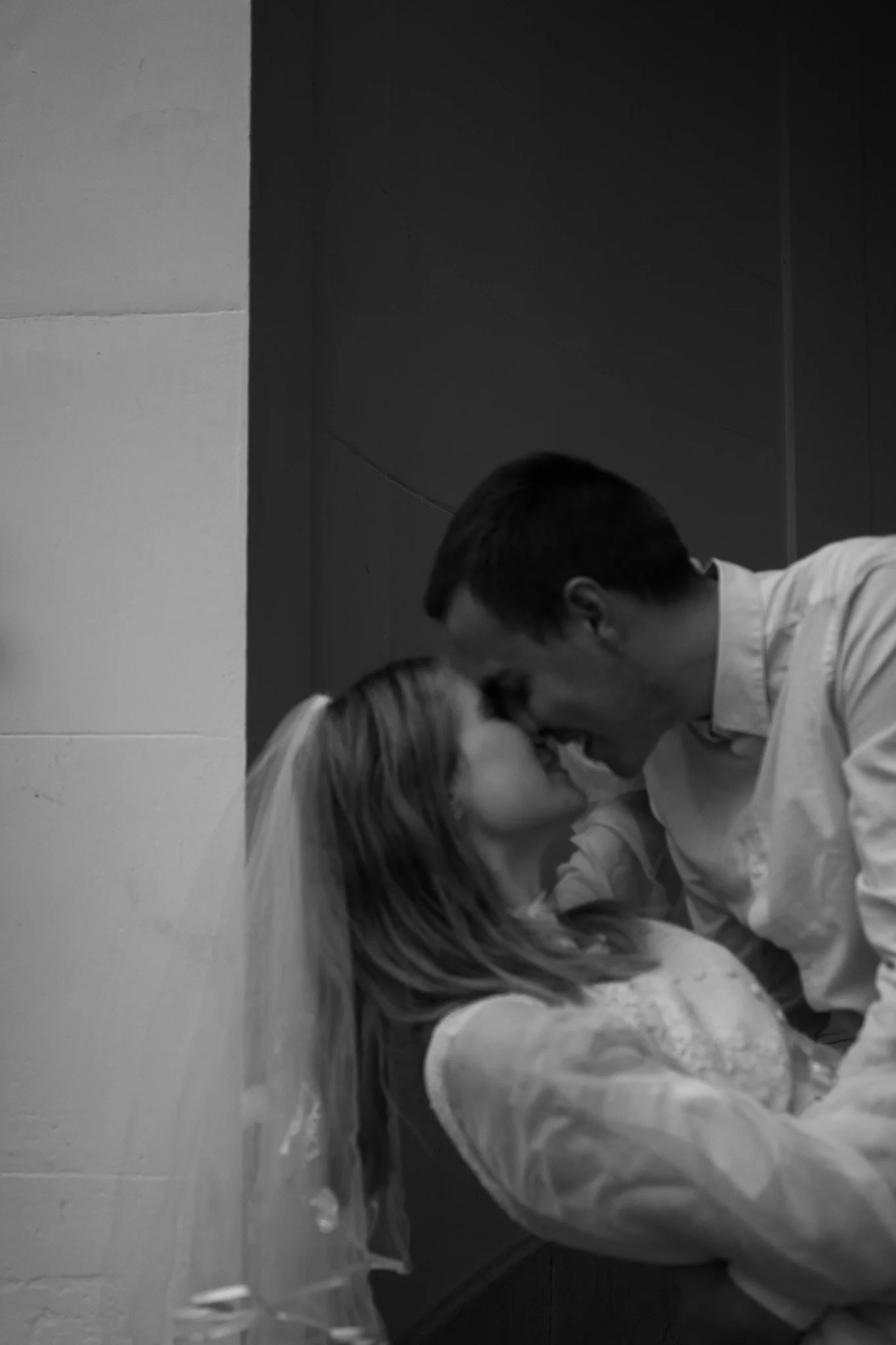 Ein Mann und eine Frau, die bei einer Hochzeit einander anschauen, mit der Stirn aneinander und lächelnd.