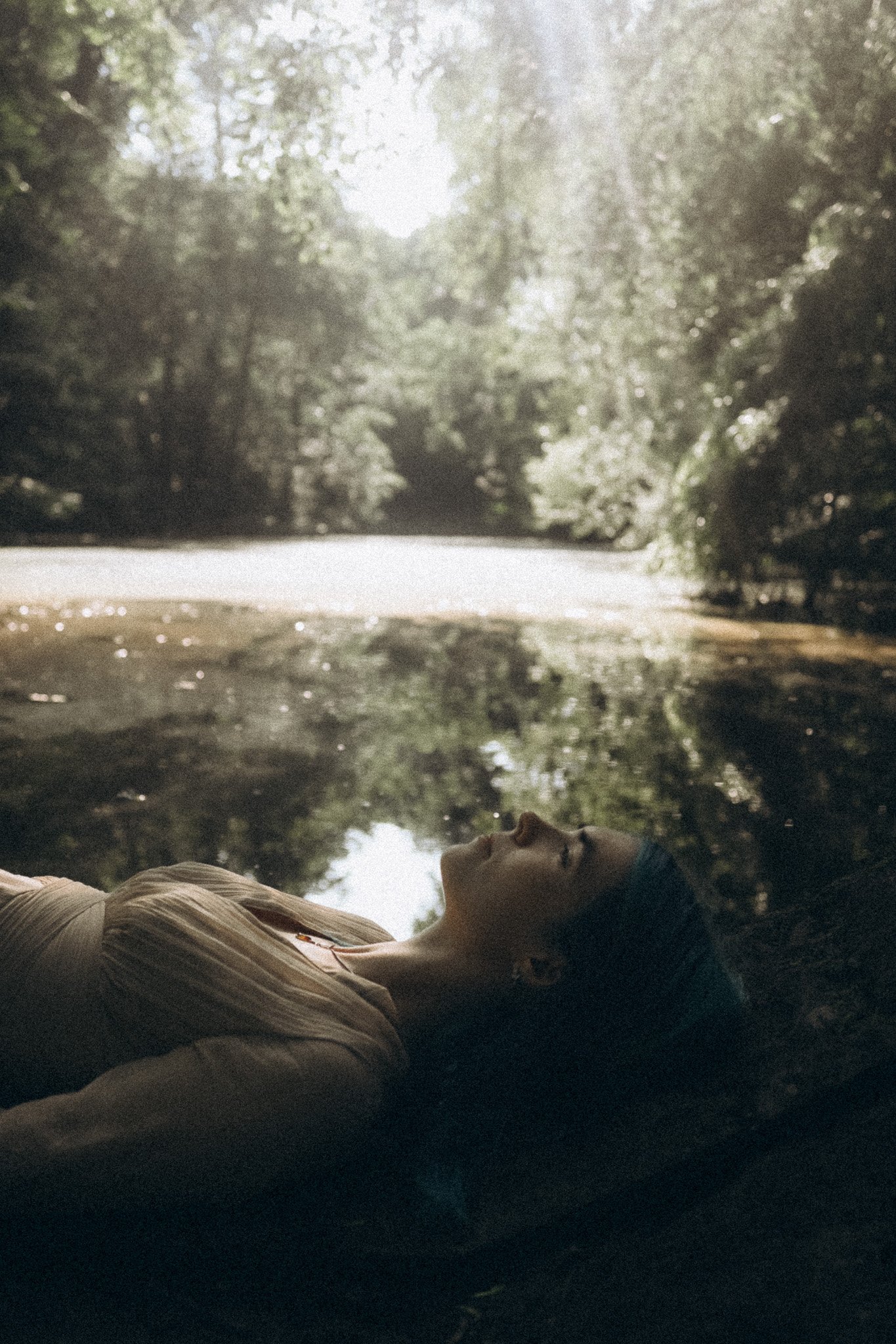 Frau liegt vor einem See und ist in iherer Mitte