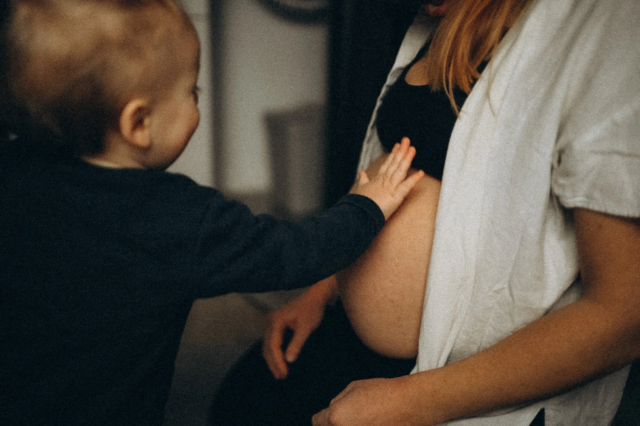 natürliche Familienfotografie in Kassel Baby greift nach Mamas schwangerem Bauch