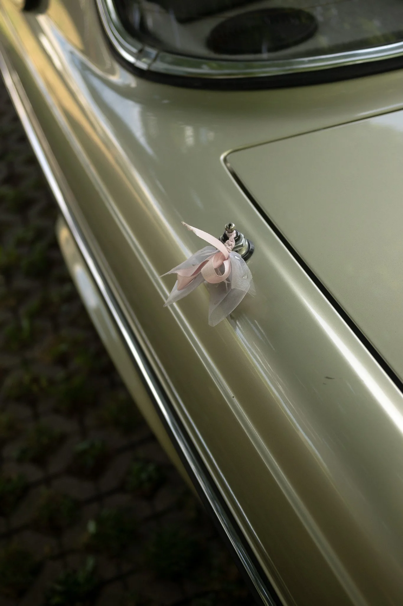 Ein alter grüner Oldtimer mit einer Schleife am Kühlergrill.