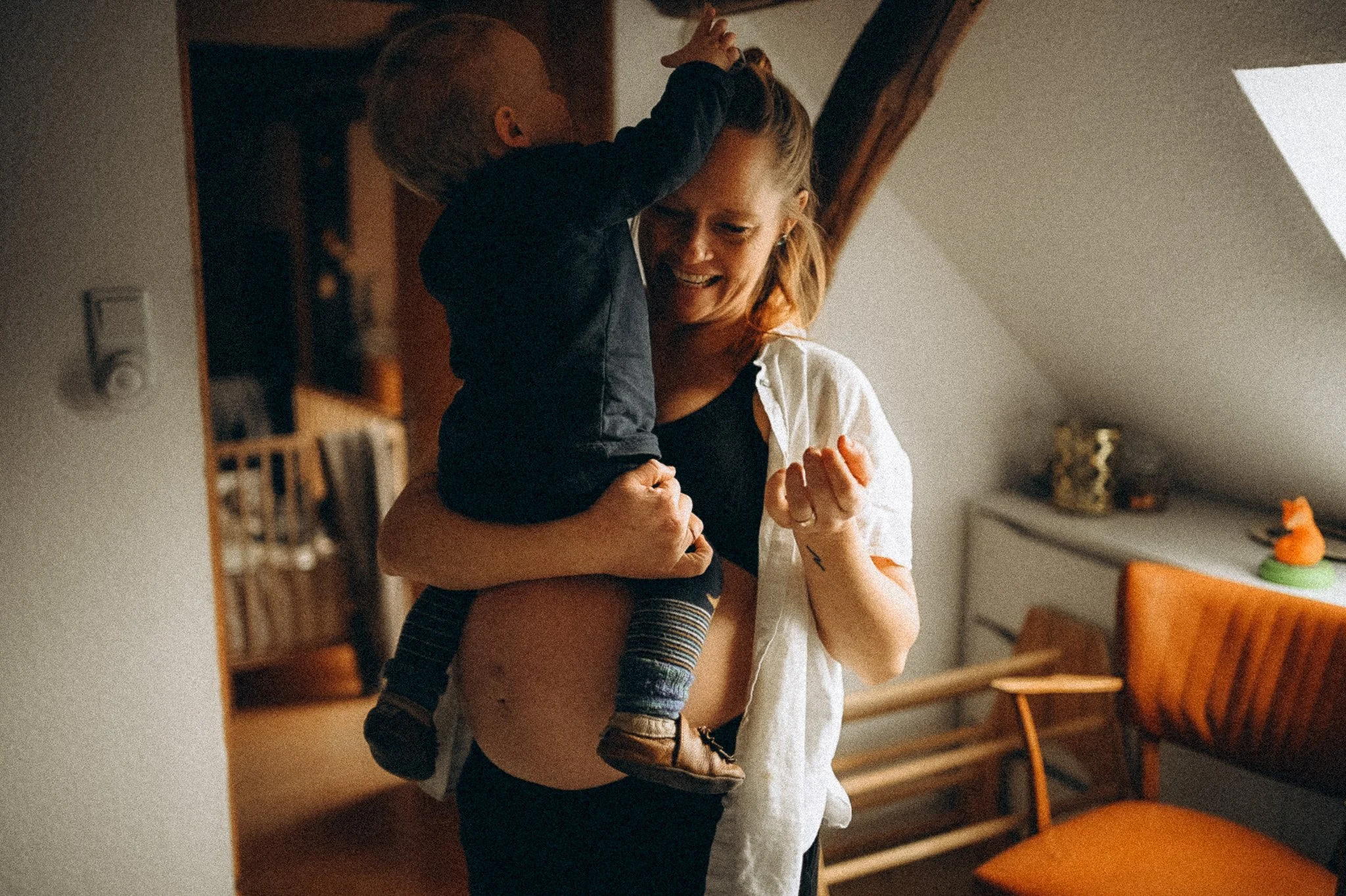 natürliche Familienfotografie in Kassel schwangere Mama bekommt Haargummi auf den Kopf gelegt zuhause