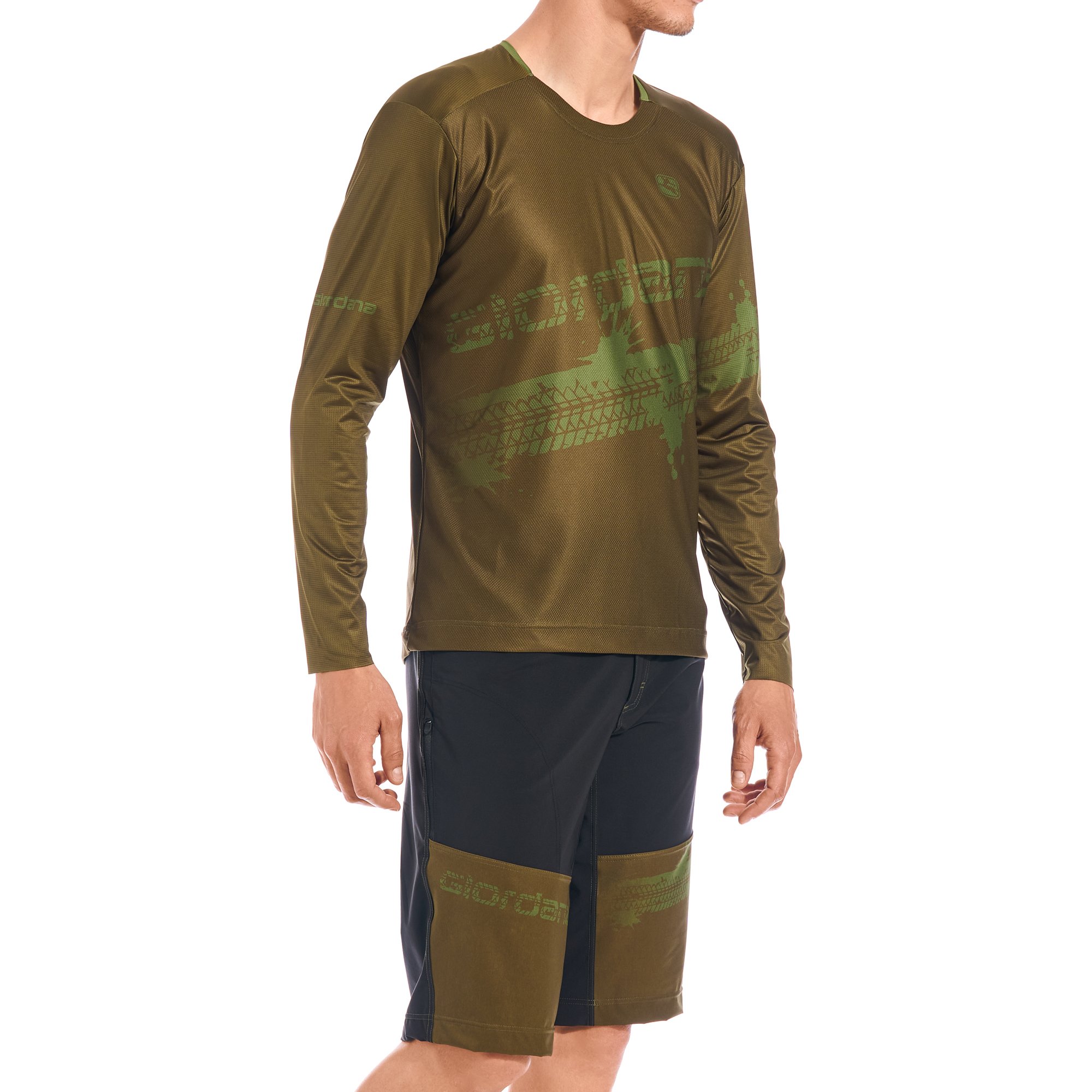 Ein Mann trägt ein langärmliges, olivgrünes Sportshirt mit schwarzen Seiteneinsätzen und einen schwarzen Shorts mit grünen Akzenten.
