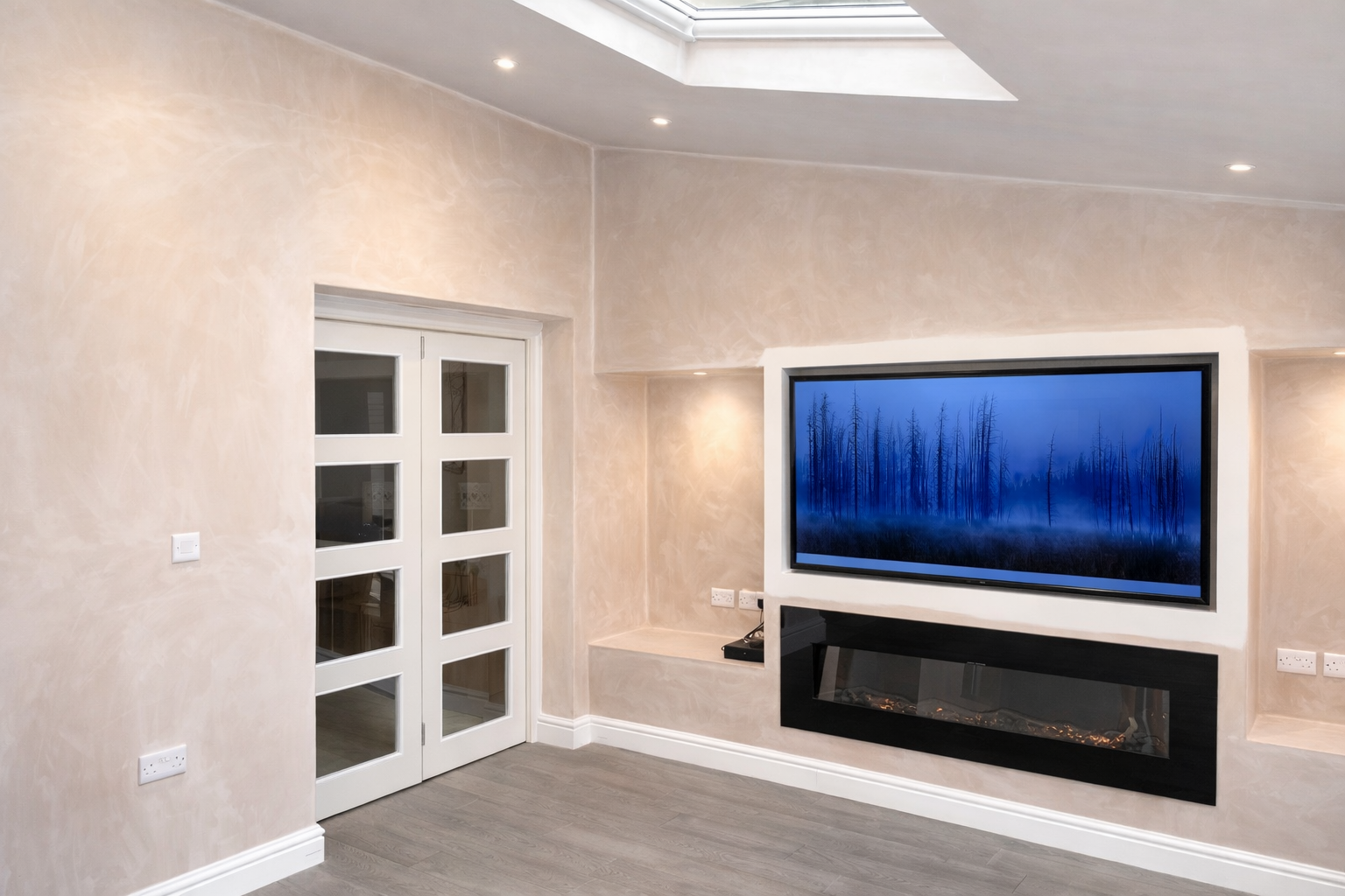 Living room with white walls, a large flat-screen TV displaying a forest scene, a modern electric fireplace below the TV, and double glass doors leading to another room.