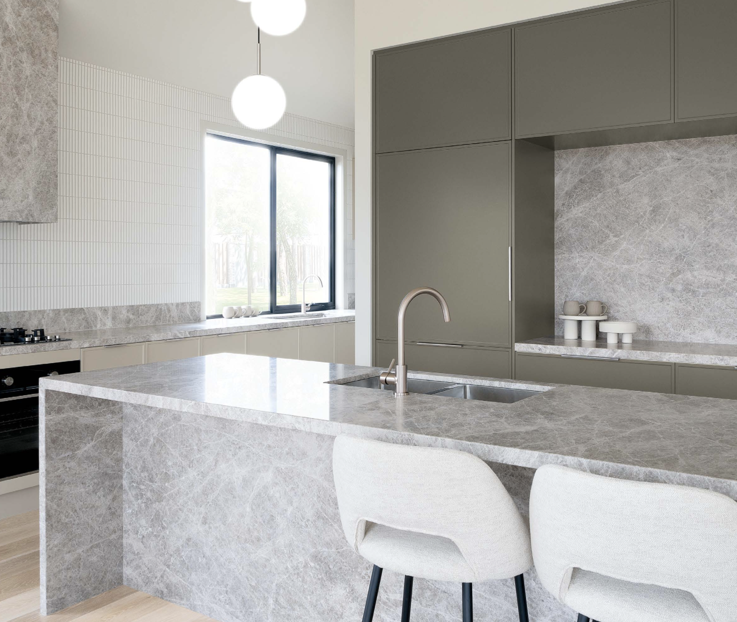 Modern kitchen with gray cabinets, marble countertops, and a large window. Features a central island with an integrated sink and two white chairs.
