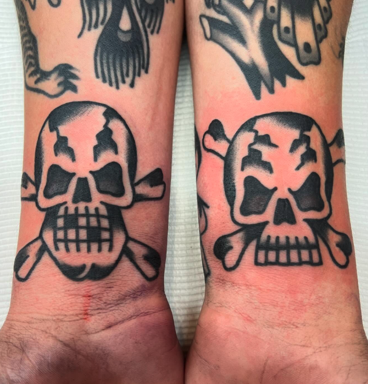 Tattoo of a skull with crossbones on each ankle.
