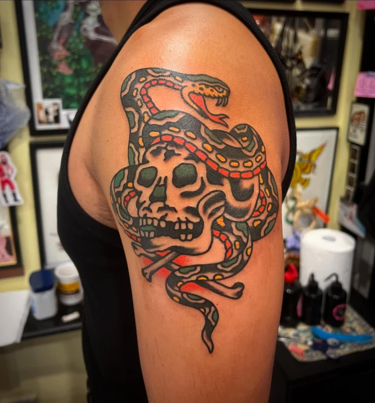 Tattoo of a snake coiled around a skull with the snake's head raised and tongue out.