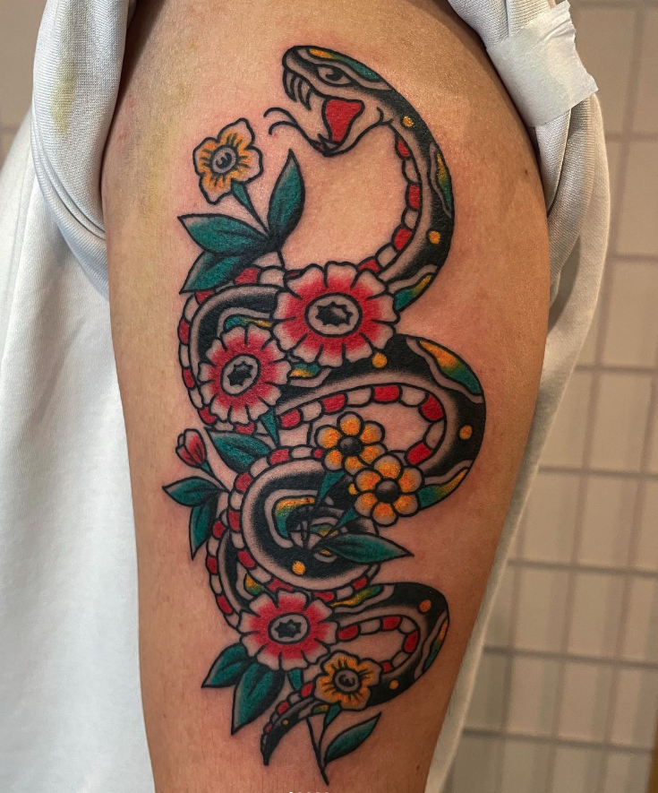 A colorful tattoo of a snake intertwined with flowers on a person's upper arm.