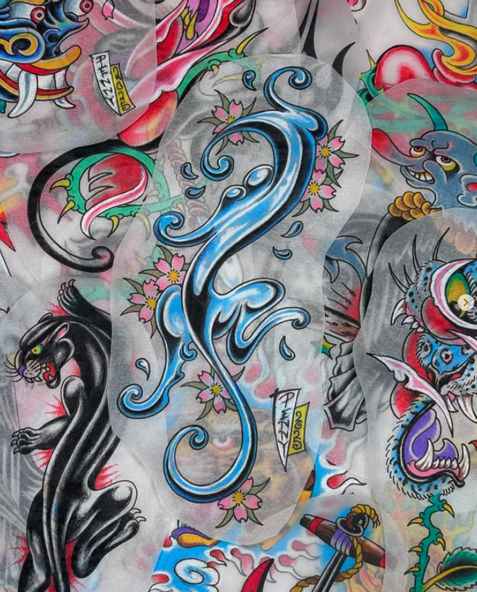 A collage of traditional American-style tattoo designs featuring a large blue swirling dragon, a black panther, pink cherry blossoms, and a fierce blue and pink tiger with tribal patterns and bold colors.