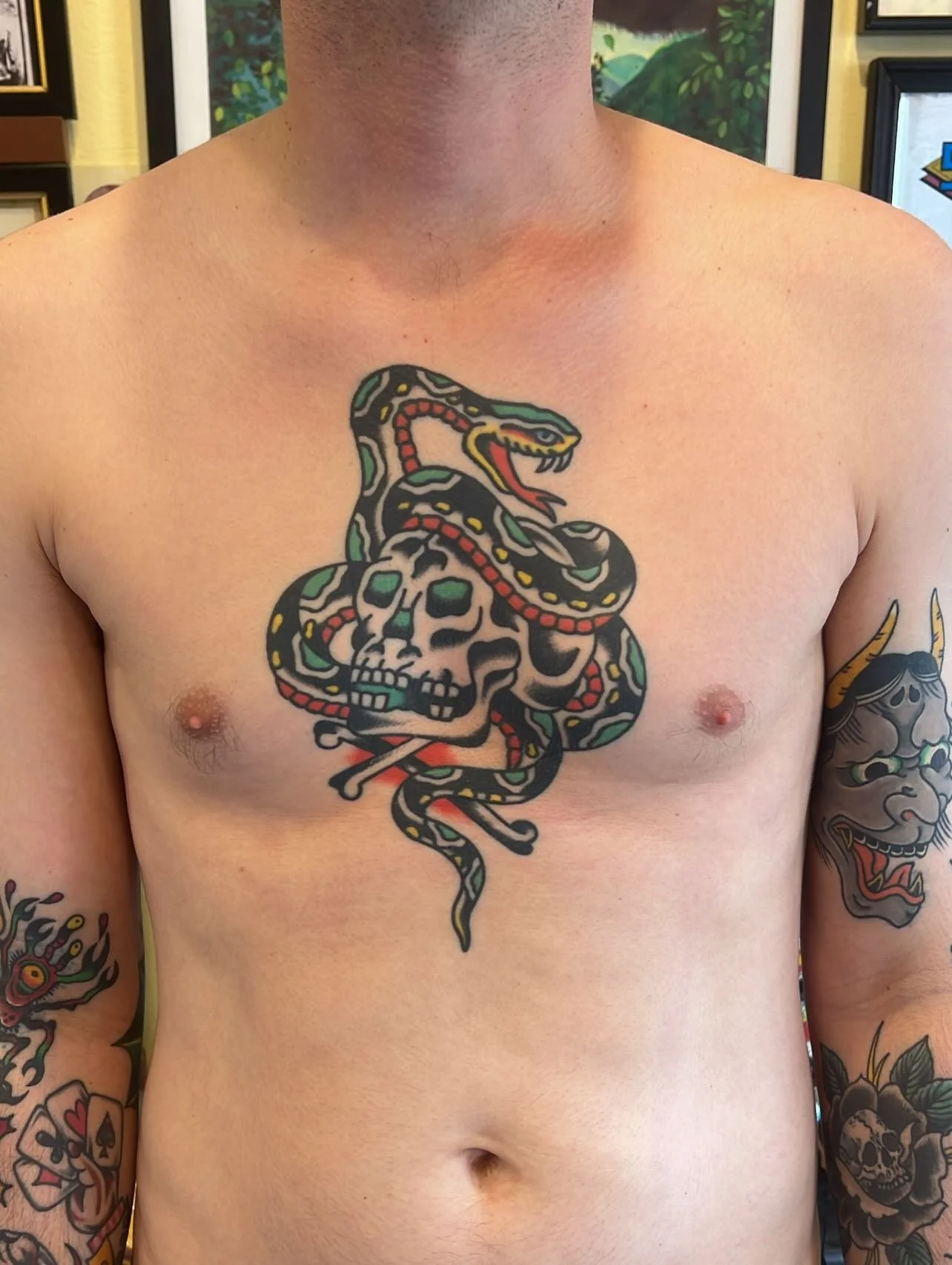 Tattoo of a snake coiled around a skull on a man's chest.