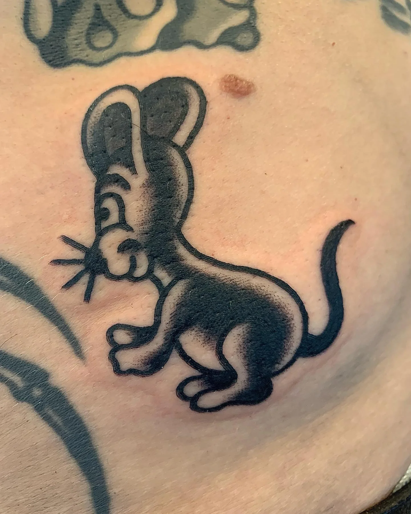 Tattoo of a cartoon mouse on a person's skin.