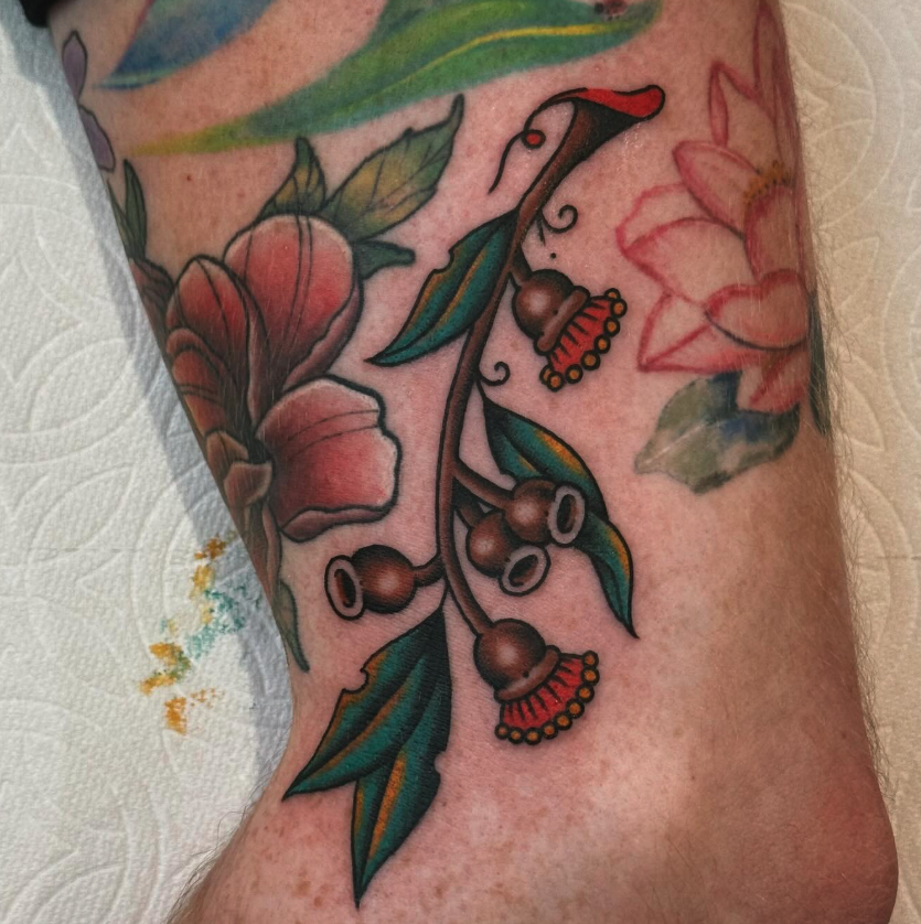 Tattoo of a branch with berries and a pink flower on a person's arm.