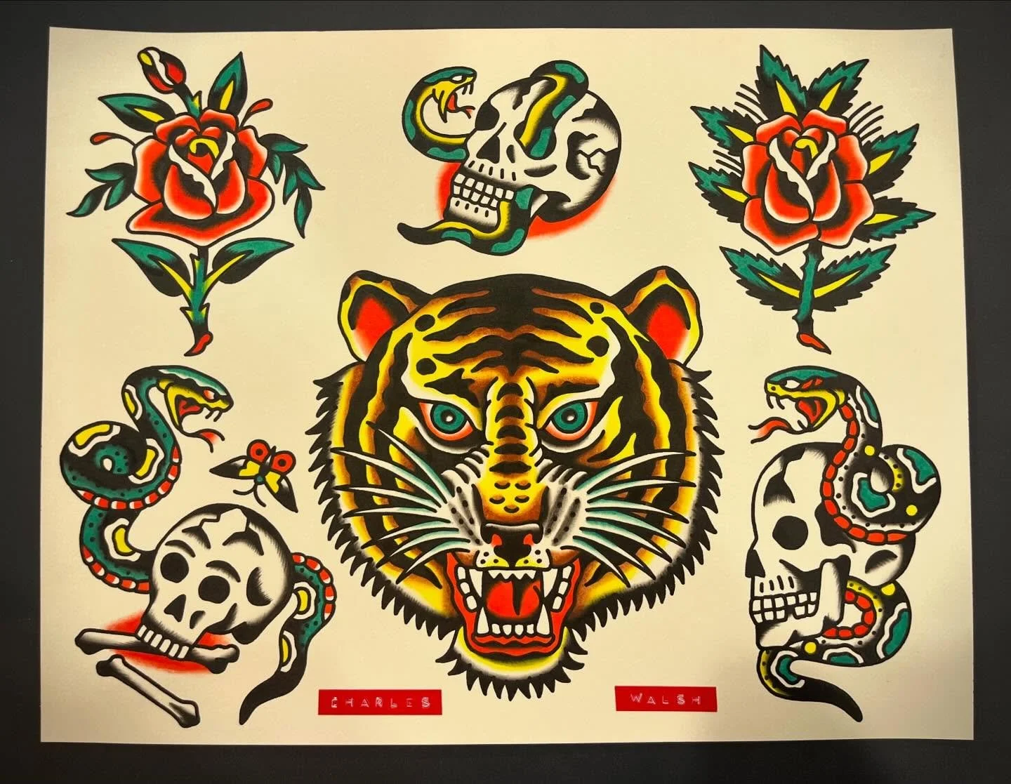 Tattoo art featuring a tiger's face in the center, surrounded by traditional motifs including roses, skulls, snakes, a snake skull, a worm, and a dragonfly, with red labels reading 'Charles Walsh' at the bottom.