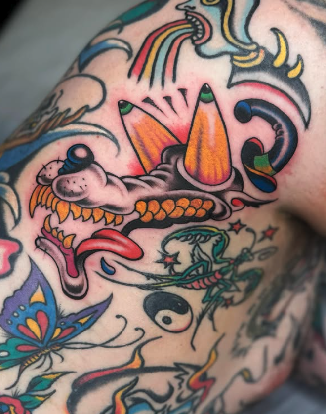 Colorful tattoo featuring a dragon, rainbow, butterfly, yin-yang symbol, and various abstract elements.