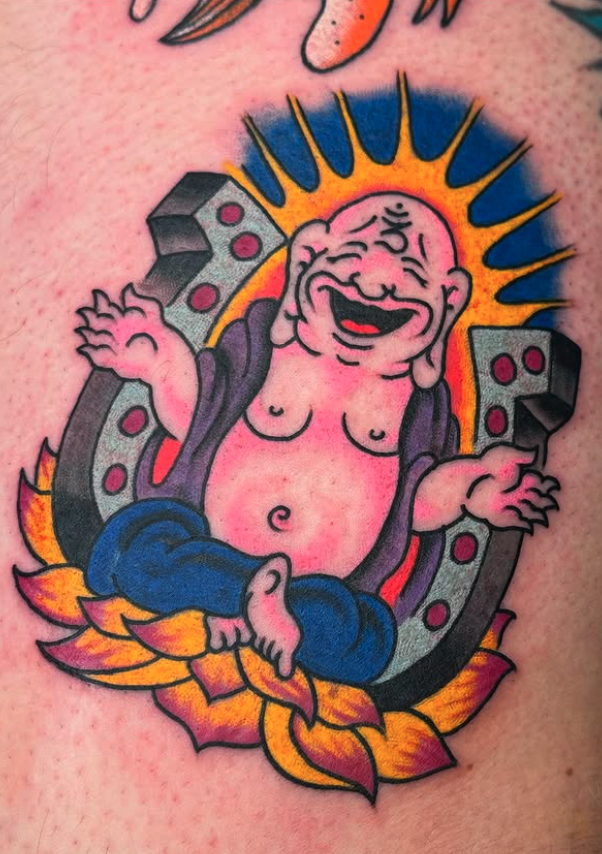 Colorful tattoo of a happy, chubby baby with a big smile, sitting on a decorative star with flames, with a bright sunburst background and houses in the design.