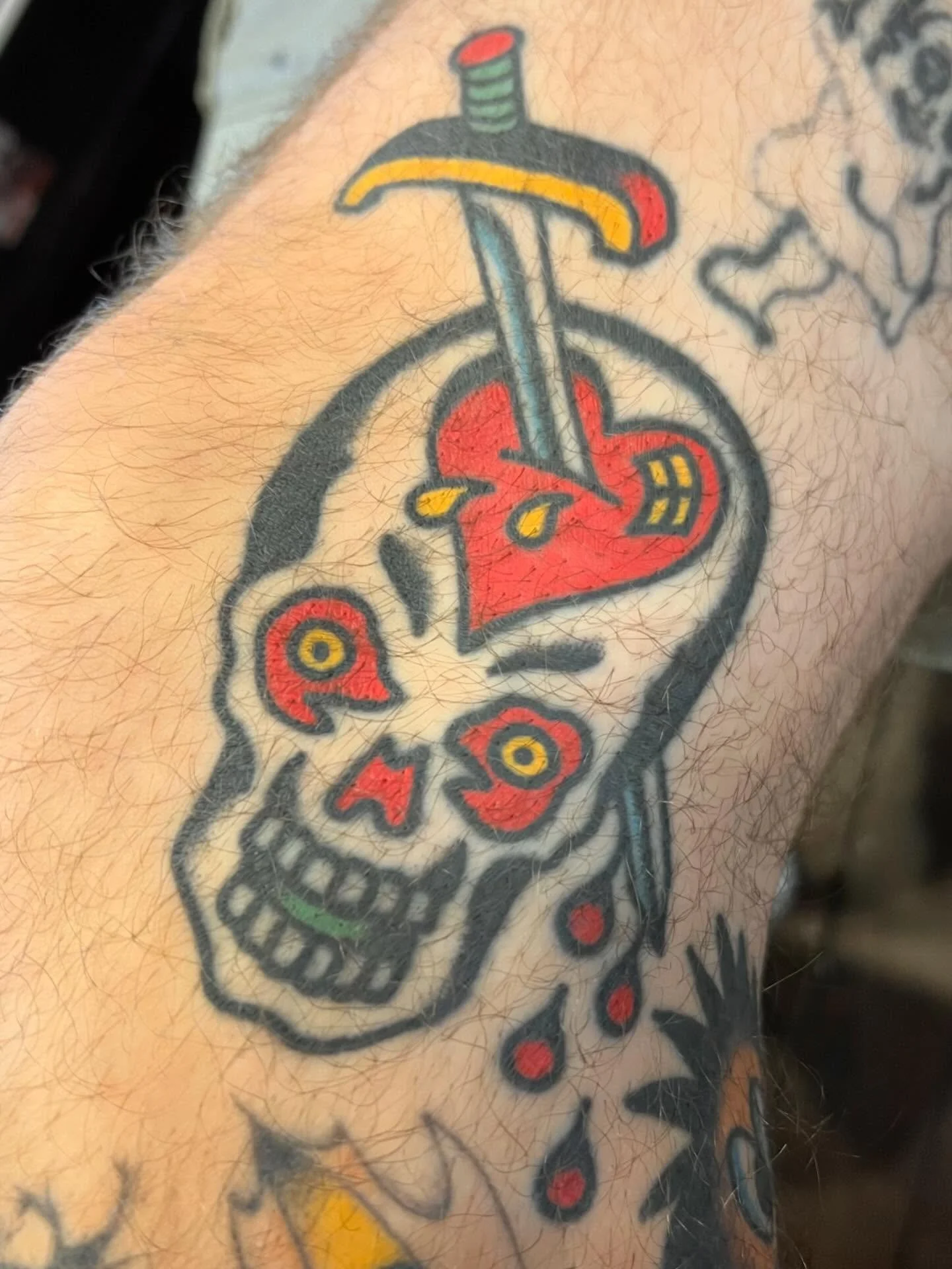 Tattoo of a skull with a hammer and sickle symbol and a dripping blood effect on the arm.