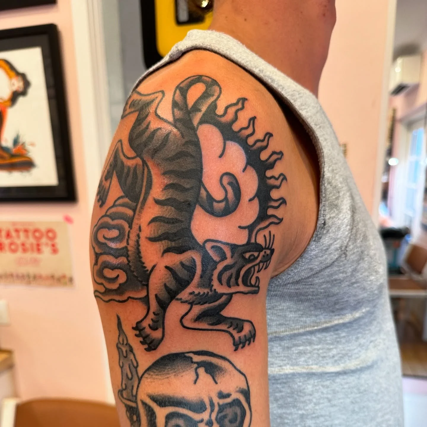 Tattoo of a dragon and a fiery skull on a person's upper arm and shoulder.