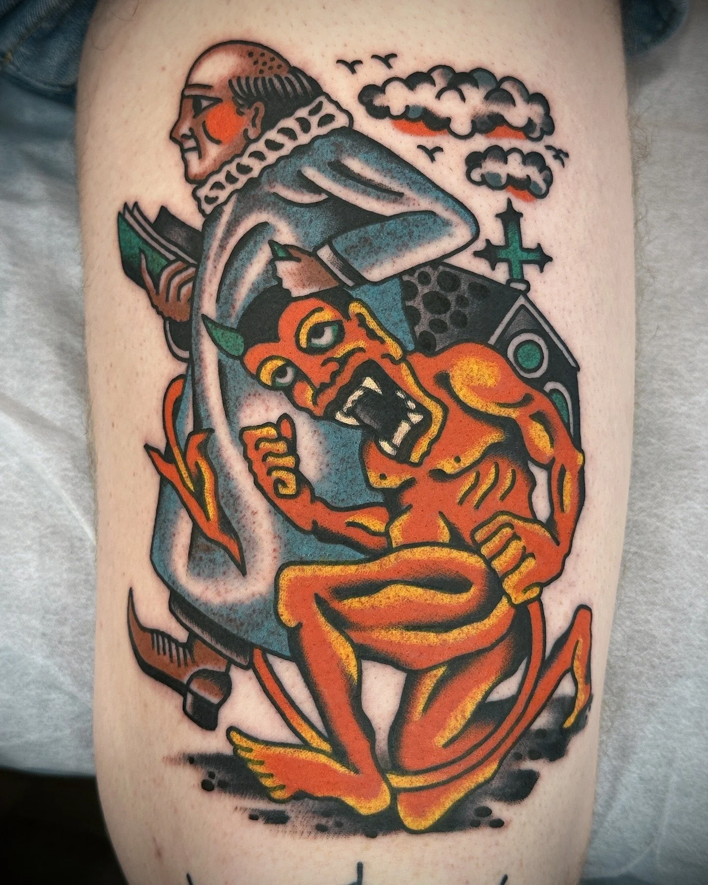 Tattoo art featuring a demon with horns and sharp teeth, wrapping around a traditional 'hot rod' style device with smoke clouds, birds, a church with a cross, and a hand holding a book.
