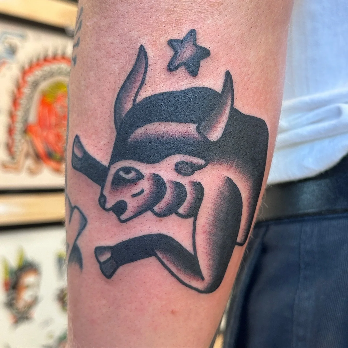 Tattoo of a unicorn with a star above its head on a person's arm.