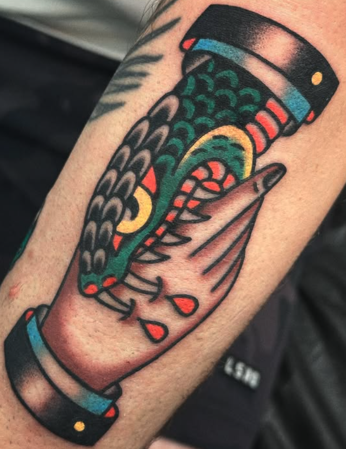 Tattoo of a colorful, stylized dinosaur skeleton inside a closed mouth with blood droplets.