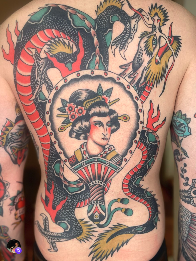 Tattoo of a geisha in traditional attire surrounded by two intertwined Japanese dragons on a person's chest.