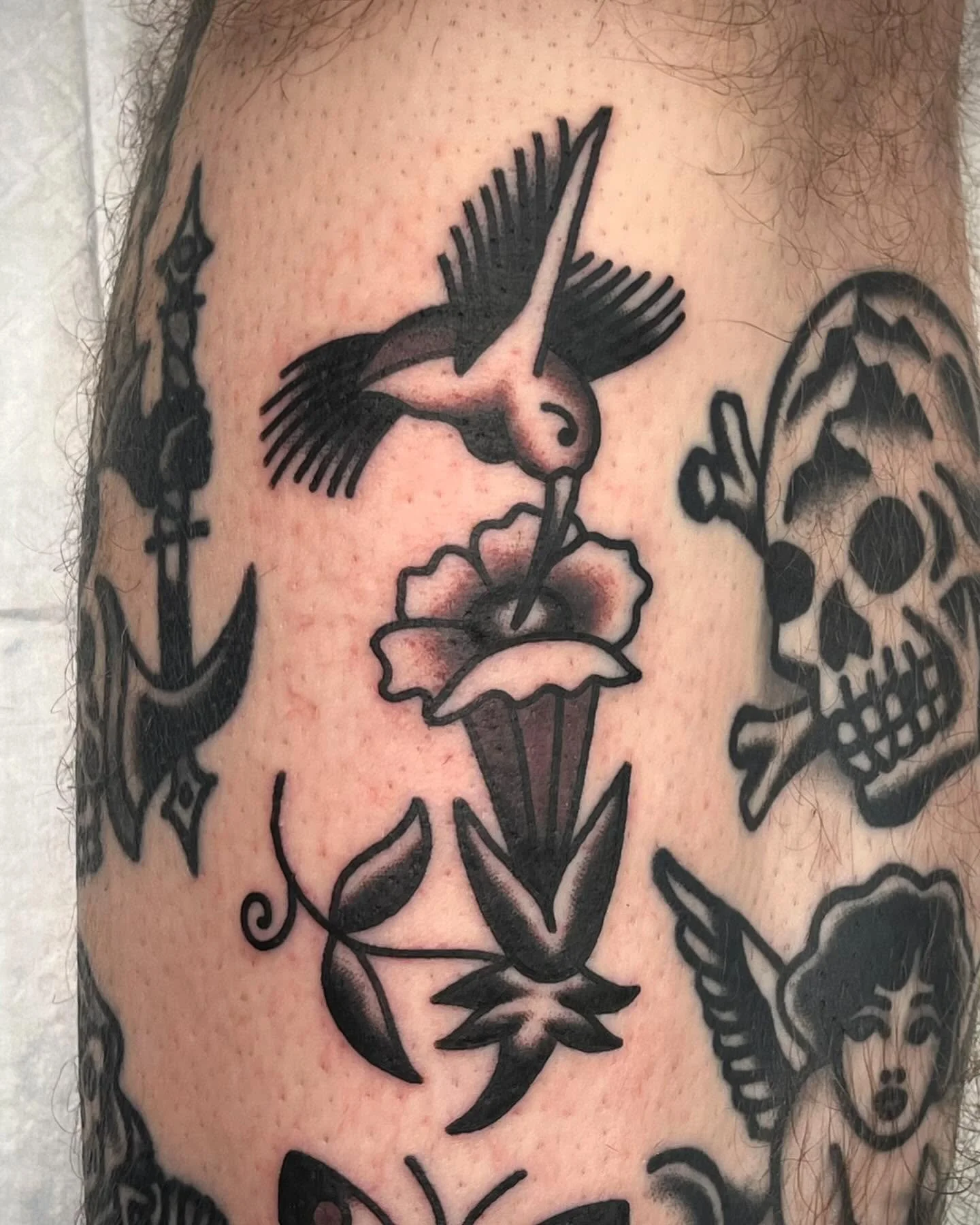 Tattoo of a bird watering a flower on the skin.