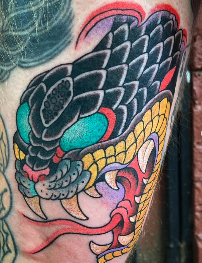 Close-up of a colorful traditional Japanese-style dragon tattoo on skin, featuring bold black outlines, red, yellow, purple, and teal colors.