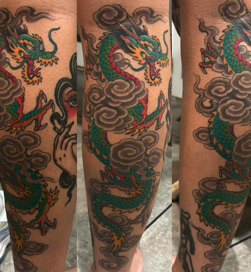 Colorful traditional Japanese dragon tattoo with clouds on arm.