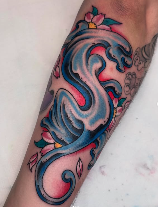 Colorful tattoo of a large stylized whale surrounded by pink and green flowers and leaves on a person's arm.