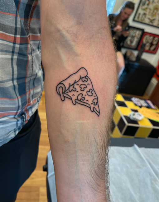 Tattoo of a slice of pizza on a person's forearm.