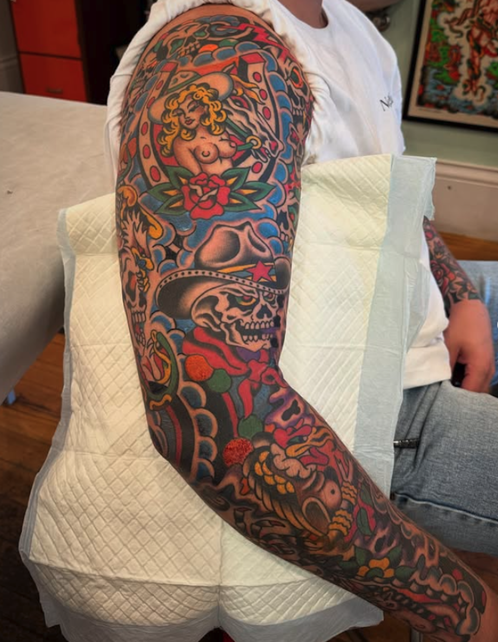 Colorful tattoo sleeve featuring a woman holding a sword, a skull with a star on its forehead, and various decorative elements.