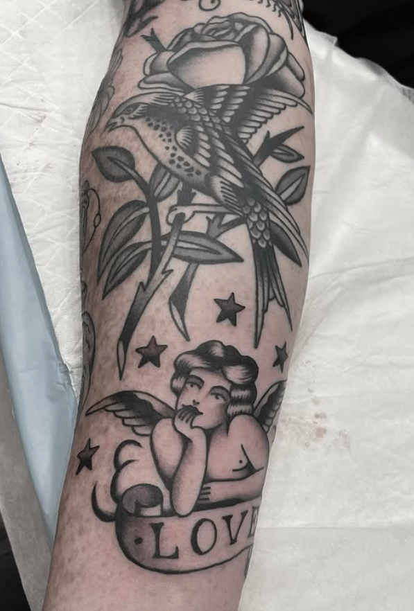Tattoo of a bird, flower, and angel with the word 'LOVE' on the arm.