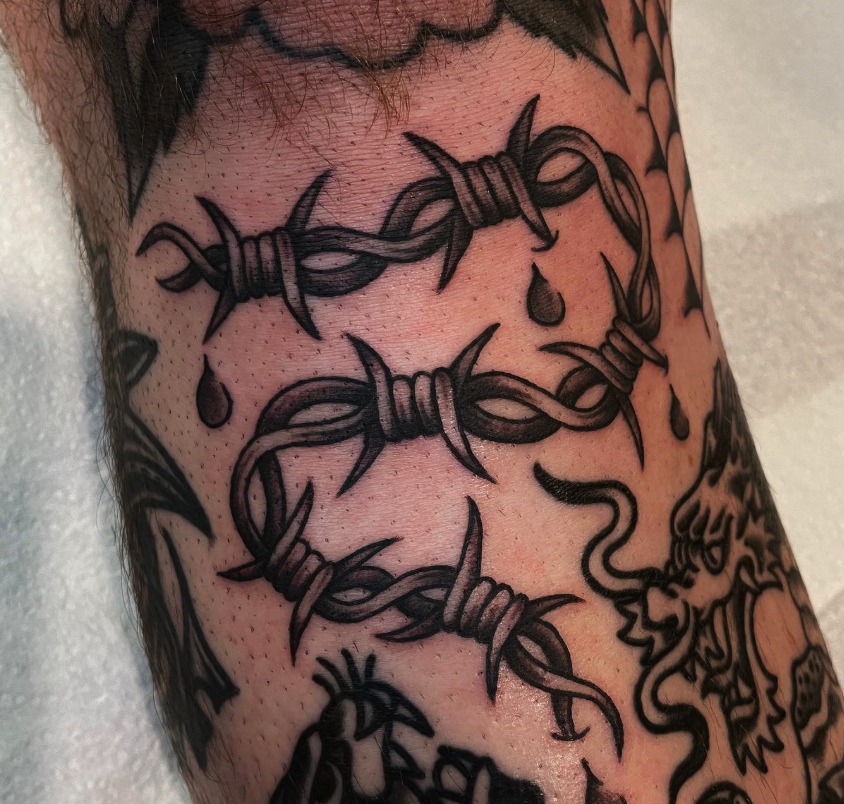 Tattoo of barbed wire with dripping drops on skin.