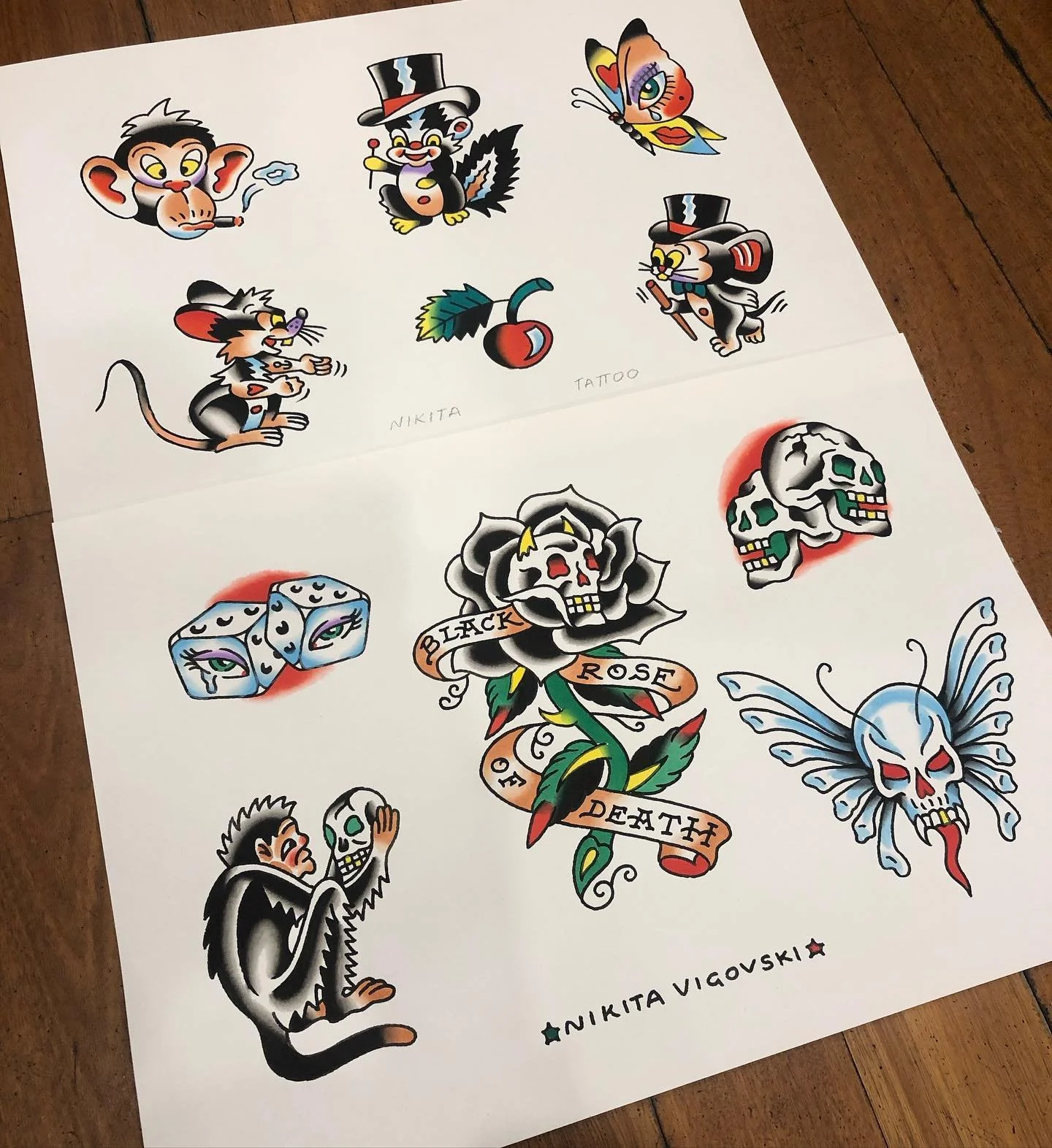 Collection of colorful tattoo-style artwork featuring various characters and symbols including monkeys, a butterfly, a cherry, skulls, dice, and a rose with a banner reading "Black Rose of Death." The artwork is signed by Nikita Vigurovski.